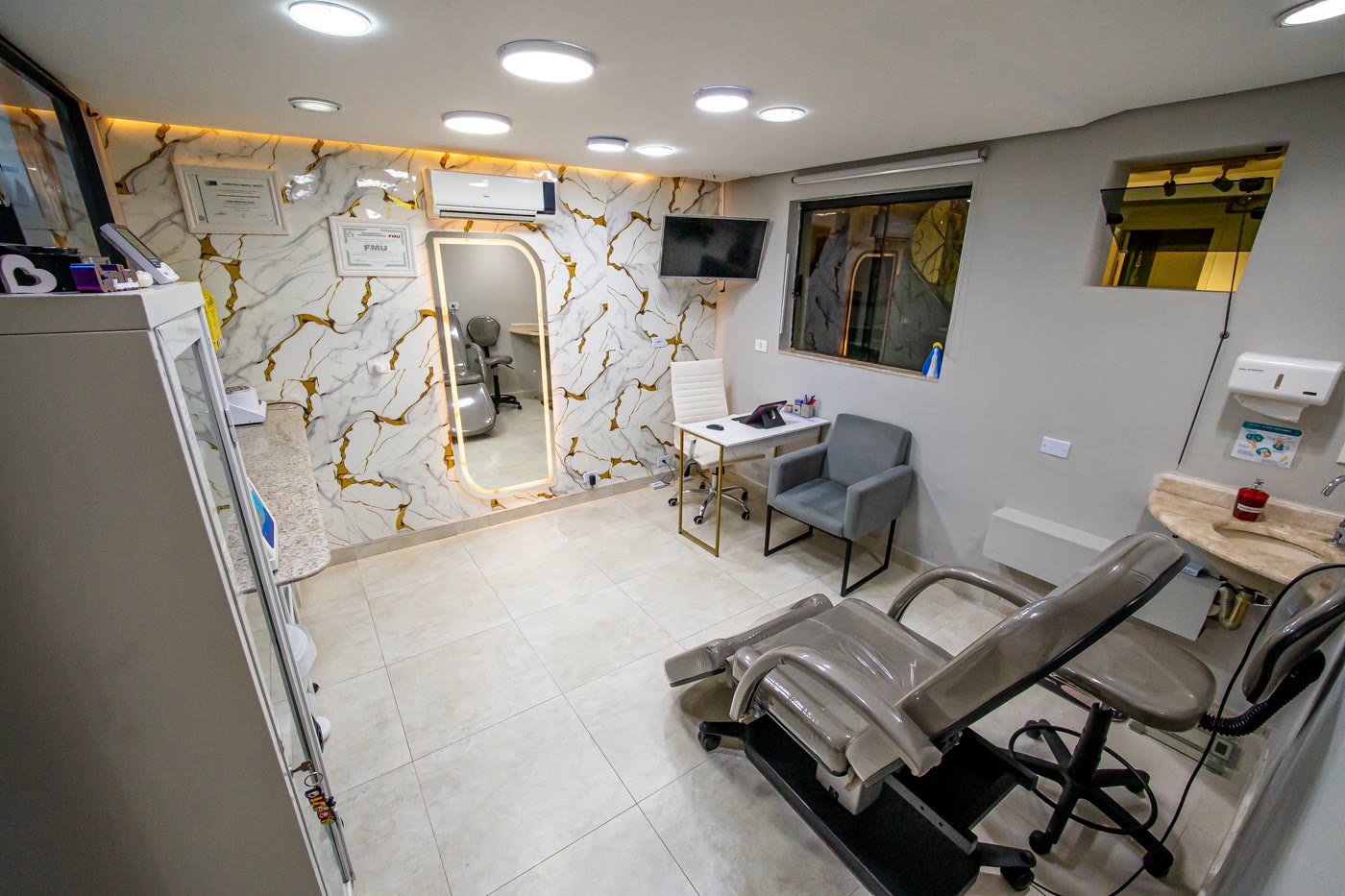 Sala de procedimentos com parede de mármore e espelho iluminado